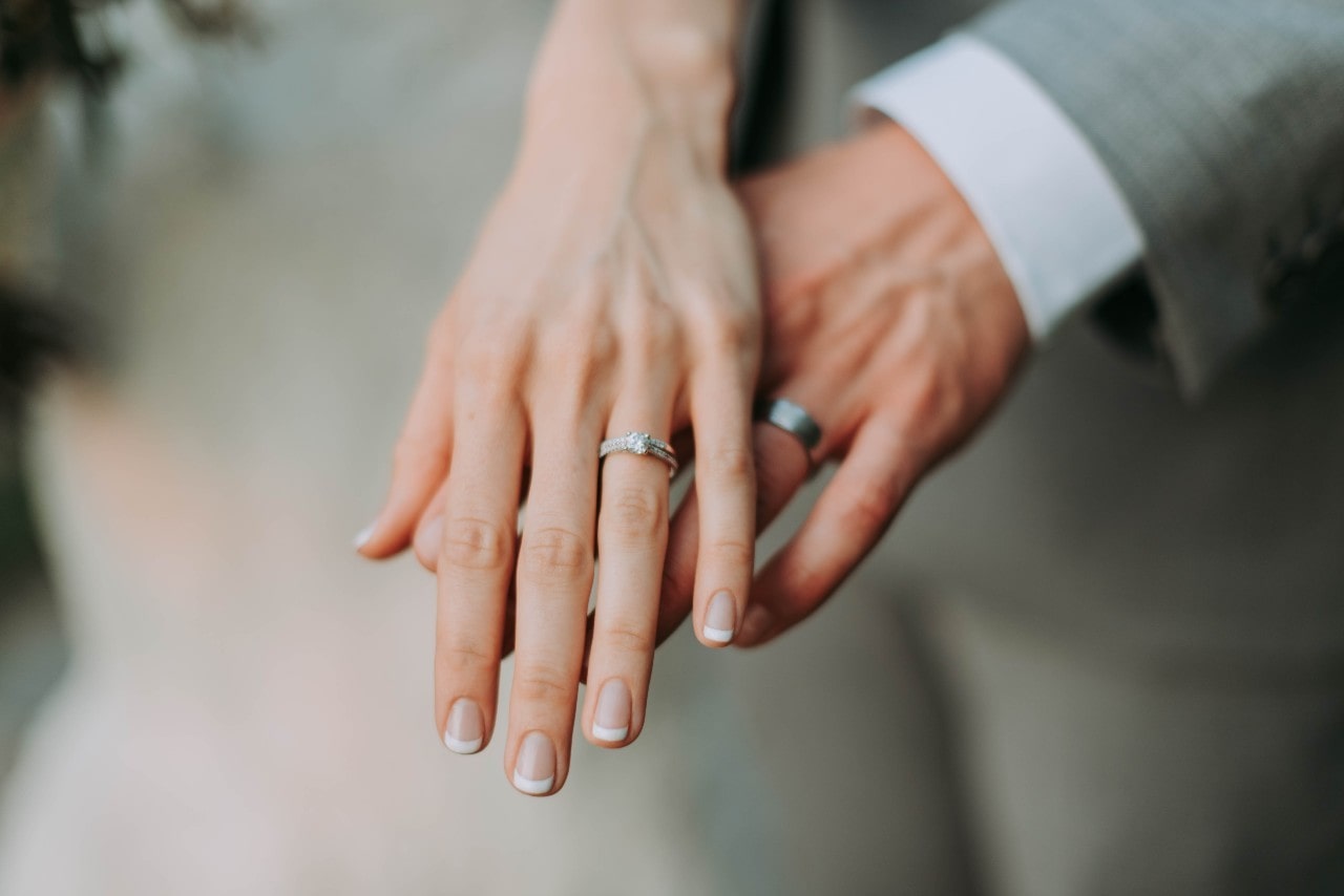 A close-up of a couple’s hands, with emphasis on their wedding bands.