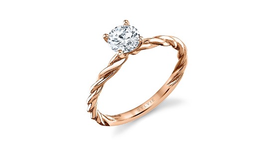 A Sylvie rose gold solitaire ring with a round cut center stone and twisted band.