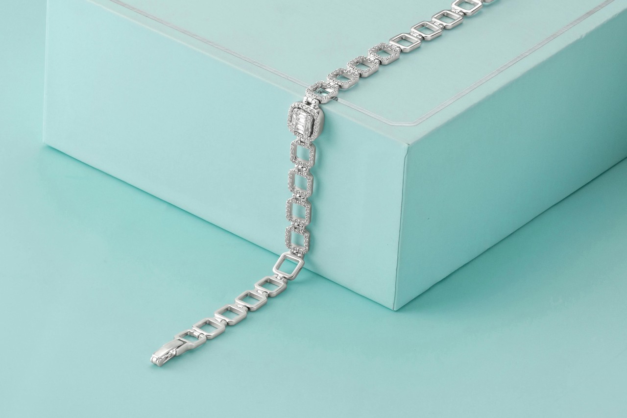A white gold diamond bracelet lying across a light blue gift box.