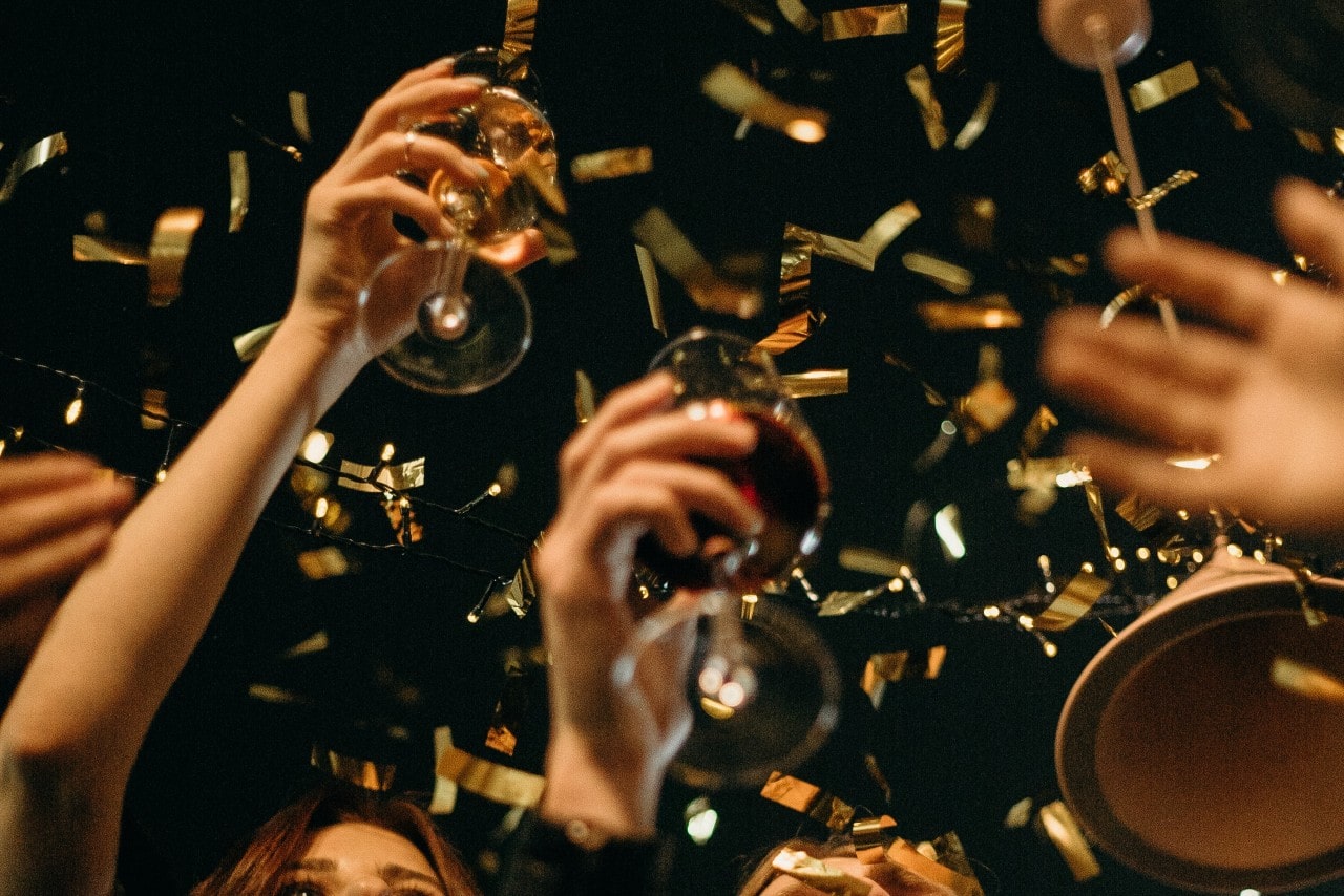 A group of friends toasting the new year as golden confetti falls.