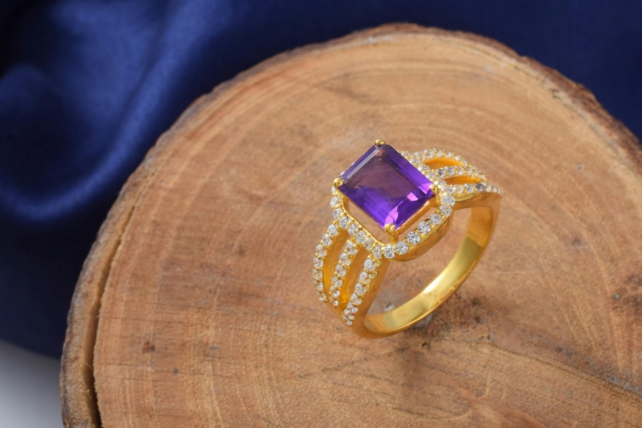 yellow gold and amethyst fashion ring sitting on a piece of wood