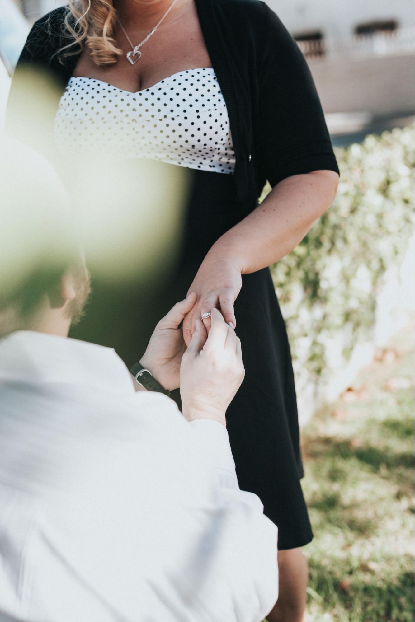 A man putting a diamond engagement ring on a woman’s hand.