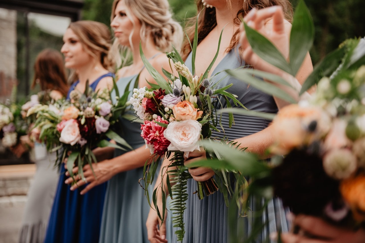 Bridesmaids holding beautifully built bouquets as they stand at the altar.