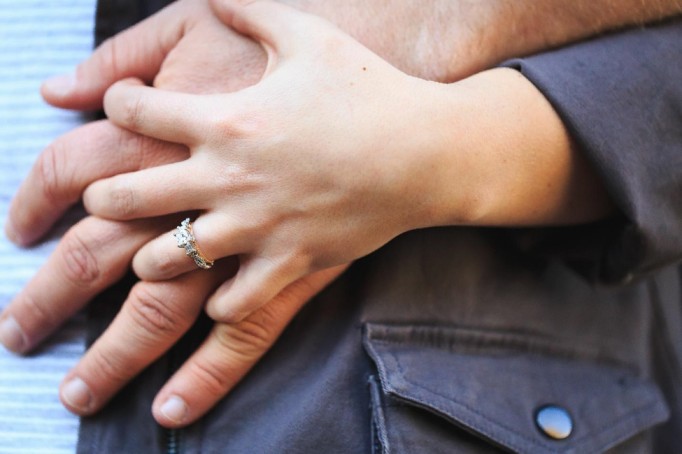 Couple holding hands together and wife shows off her engagement ring