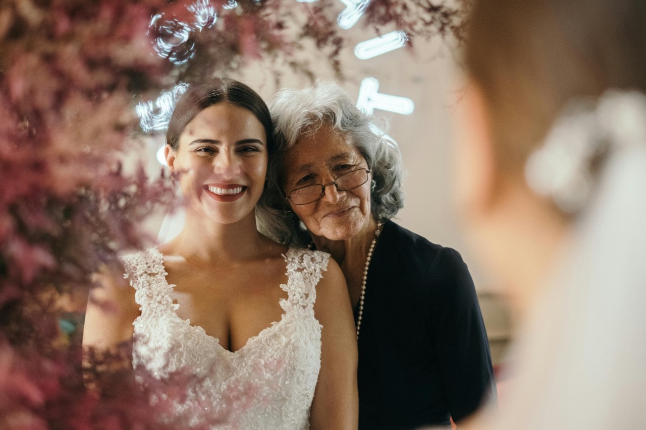 A bride and her grandmother looking emotionally into the mirror admiring her wedding dress. A bride and her grandmother looking emotionally into the mirror admiring her wedding dress.