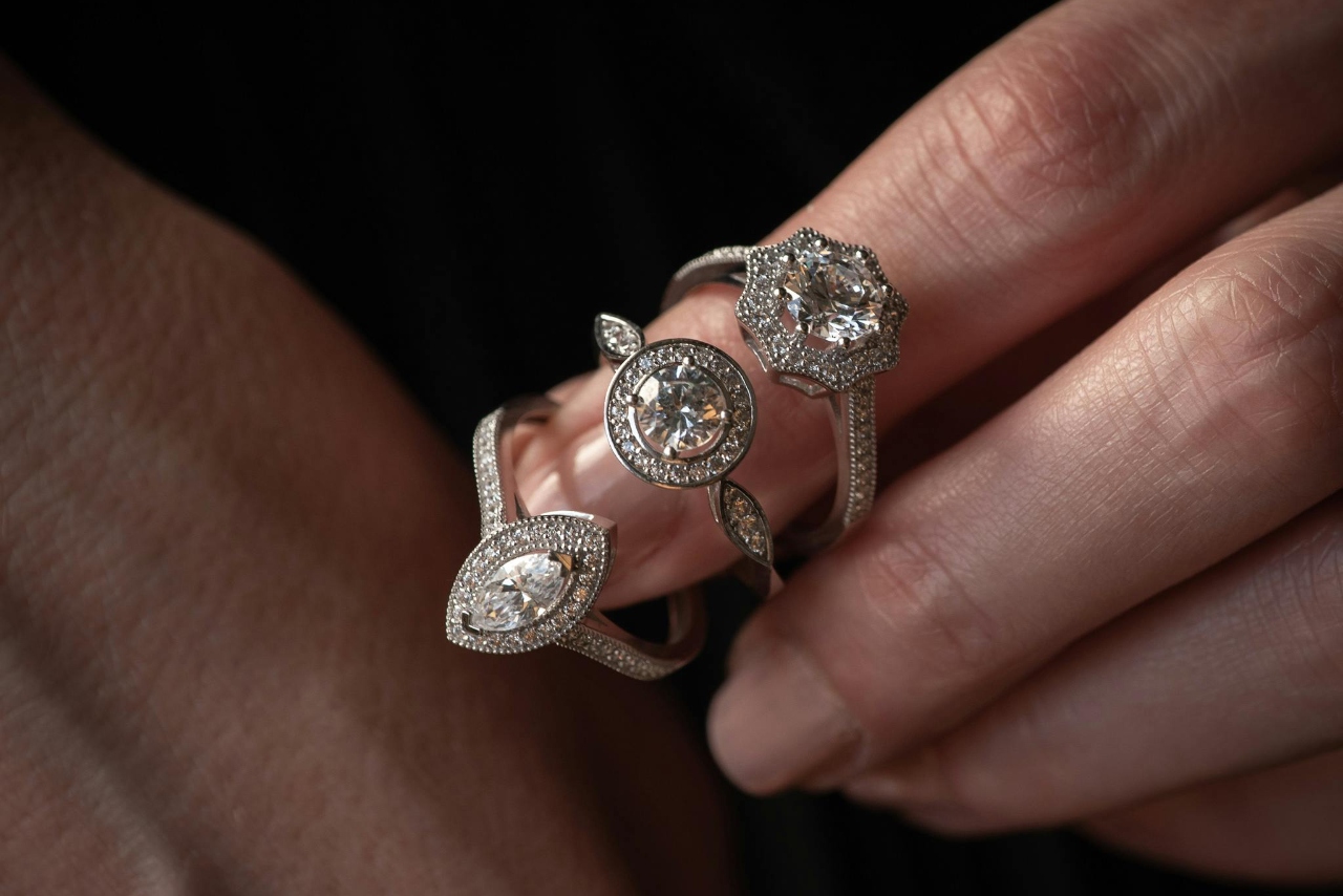 Close-up of a person wearing three distinct diamond wedding rings on their fingers. Close-up of a person wearing three distinct diamond wedding rings on their fingers.