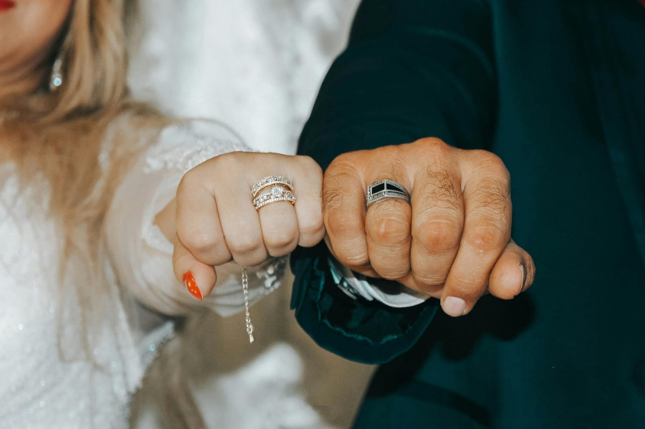 Bride and groom bumping fists to show off their diamond and signet wedding rings. Bride and groom bumping fists to show off their diamond and signet wedding rings.
