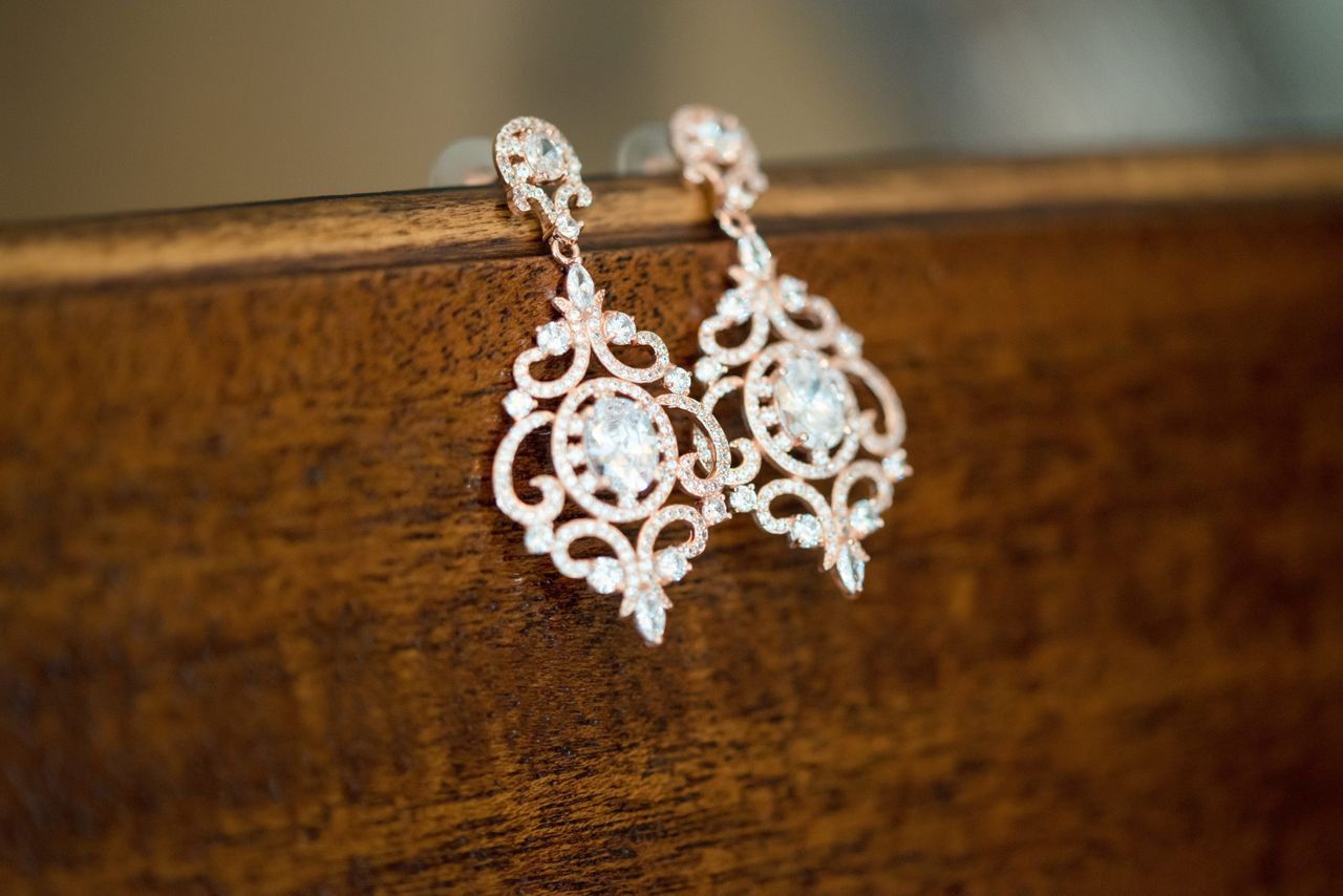 A pair of stunning diamond earrings on the lip of a wooden table A pair of stunning diamond earrings on the lip of a wooden table