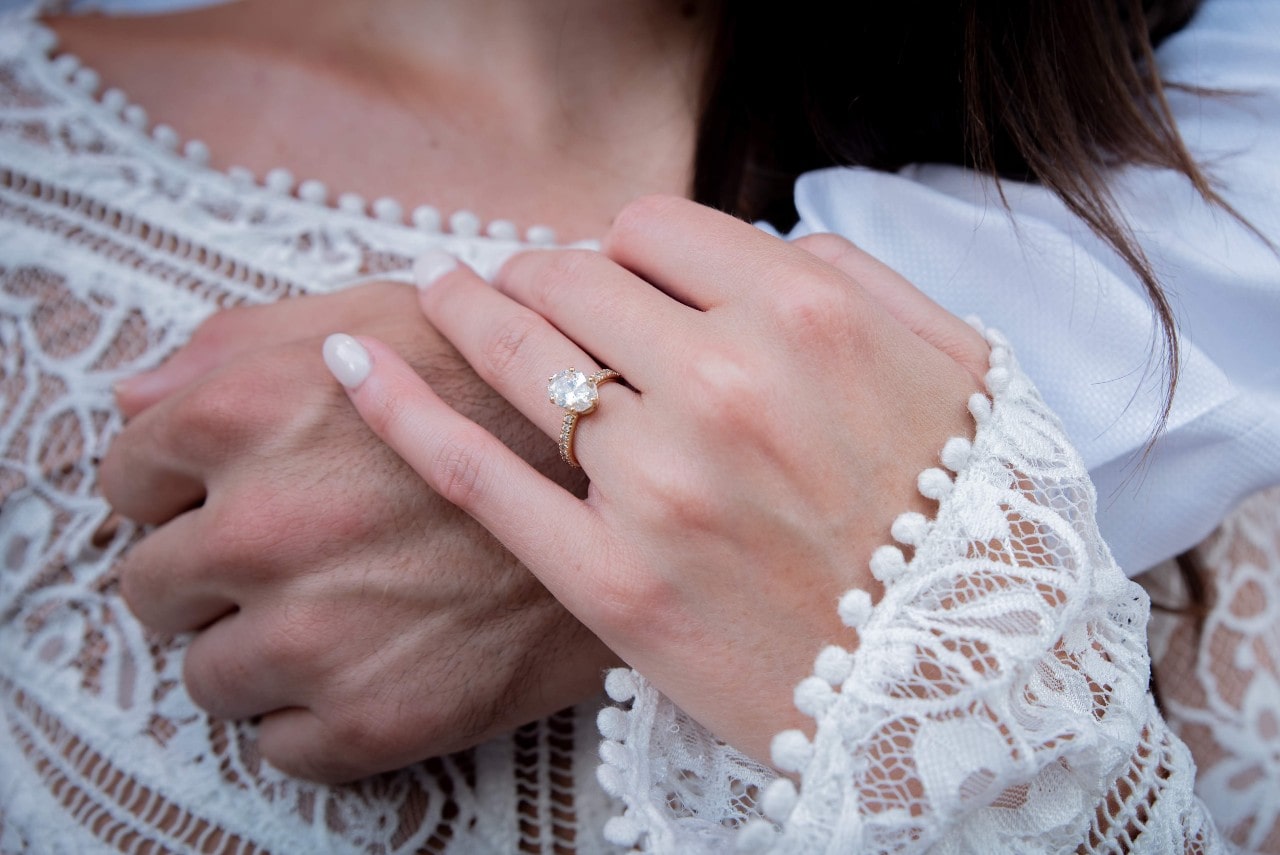 close up of couple's hands wearing a diamond engagement ring