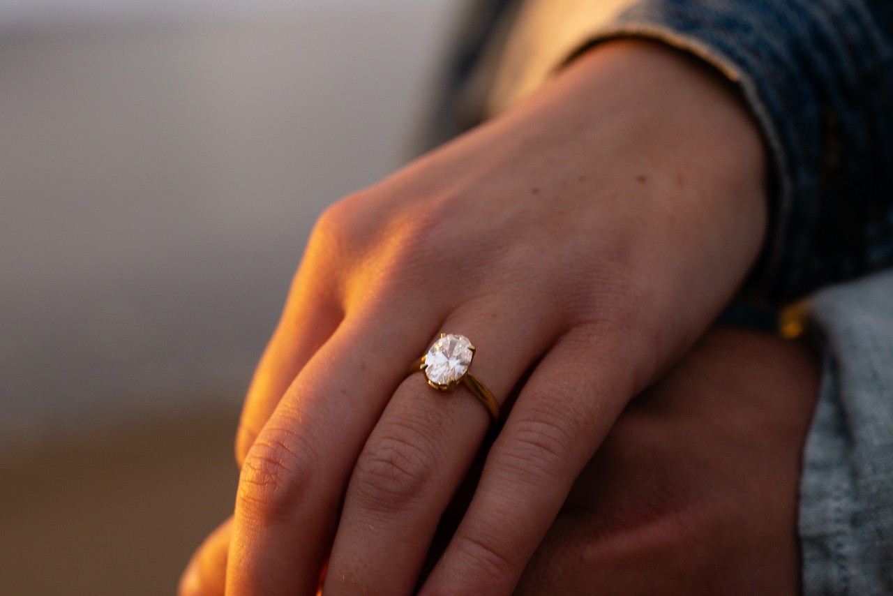 a couple holding hands wearing solitaire engagement ring