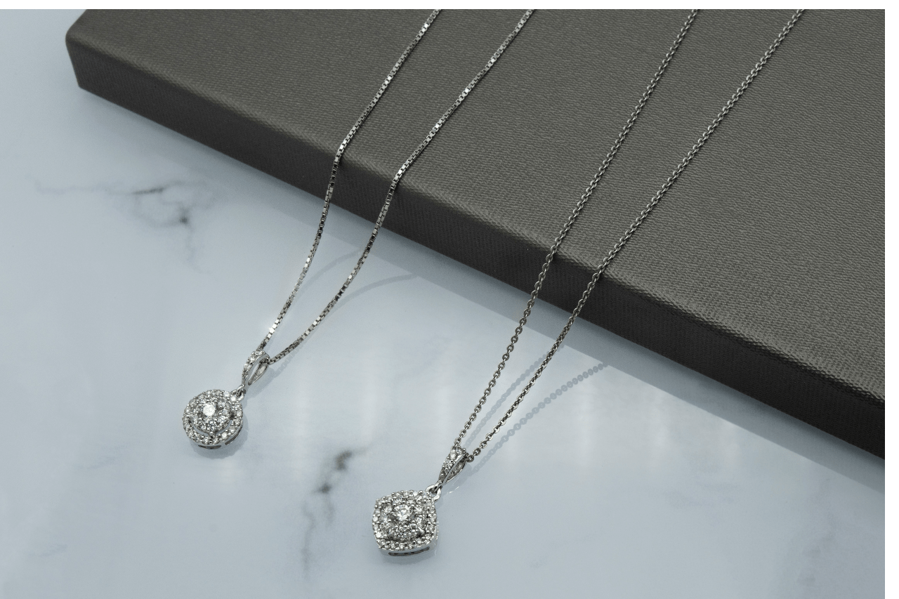 Two white gold diamond pendant necklace on a marble surface Two white gold diamond pendant necklace on a marble surface